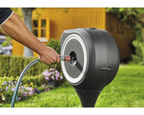 Scène de jardin avec un coffre de tuyau et une personne connectant un tuyau d''arrosage.