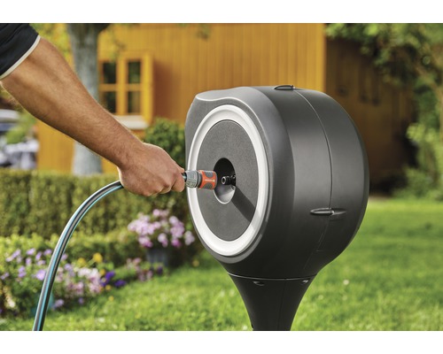 Scène de jardin avec un dévidoir sur une pelouse avec des fleurs et une cabane de jardin en arrière-plan