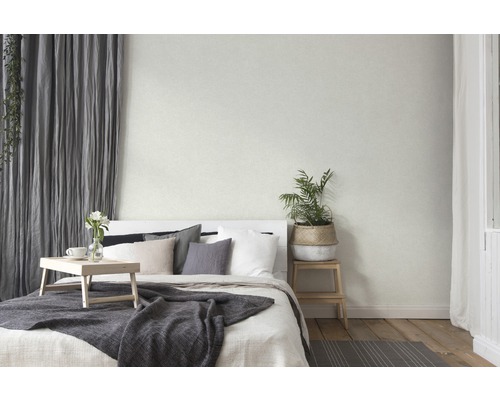Helles Schlafzimmer mit Bett, Textilien und Zimmerpflanze