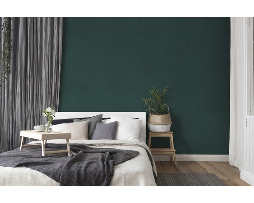 Schlafzimmer mit Bett, Beistelltisch und grüner Wand