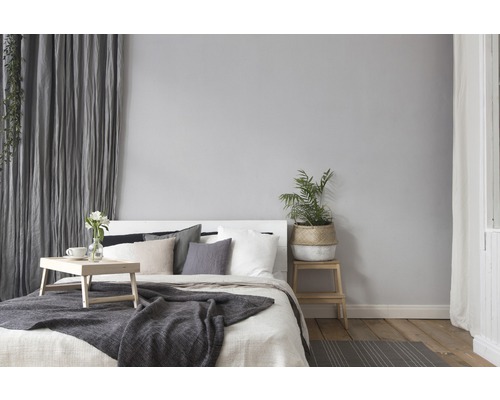 Schlafzimmer mit Bett, Kissen, Tagesdecke, Vorhängen und Pflanze