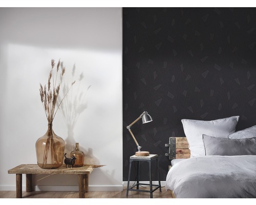 Schlafzimmer mit Bett, Lampe und Dekoration vor einer Wand mit geometrischer Tapete