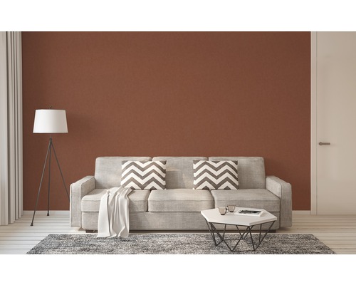 Salon avec canapé, coussins, table et lampadaire devant un mur marron