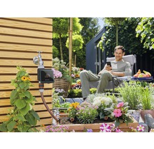 Système d''arrosage de jardin avec commande numérique et homme détendu à l''arrière-plan