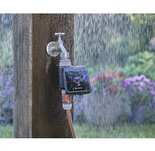 Robinet Gardena avec programmateur d''arrosage et tuyau d''arrosage connecté sous la pluie