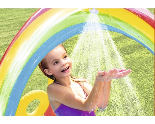 Fille jouant avec un arroseur arc-en-ciel dans le jardin