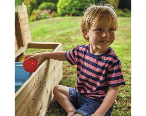Garçon assis à côté d''un coffre à jouets en bois ouvert avec des jouets