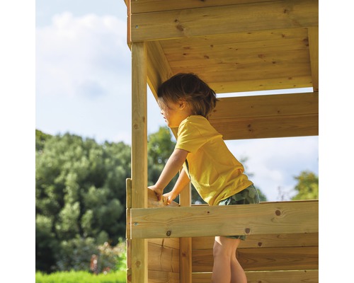 Un enfant joue dans une cabane en bois dans le jardin