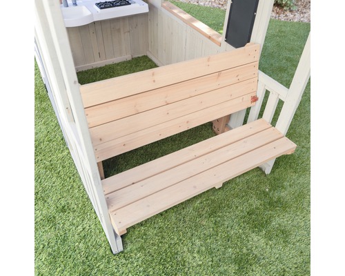 Gros plan d''une cabane de jeu avec des bancs en bois sur une pelouse.