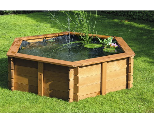 Bassin de jardin hexagonal en bois avec plantes aquatiques et fontaine sur pelouse