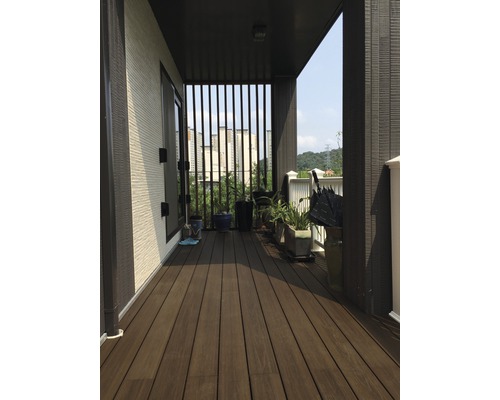 Balcon couvert avec terrasse en bois, plantes et vue sur la ville.