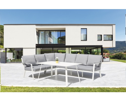Ensemble de mobilier de jardin avec canapé d''angle et table sur une terrasse devant une maison moderne.