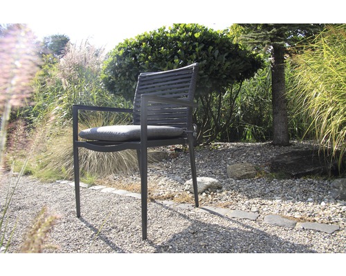 Gartenstuhl mit Armlehnen und Sitzkissen vor Grünpflanzen