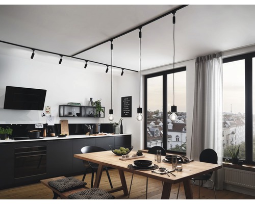 Cuisine claire avec table à manger, chaises et kitchenette noire sous un système de rails d''éclairage