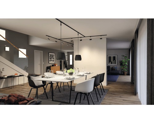 Salle à manger lumineuse avec table, chaises et spots sur rail.