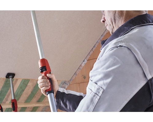 Handwerker verwendet eine Teleskopstange zur Montage von Gipskartonplatten an einer Decke.