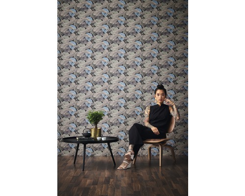 Raumansicht mit gemusterter Tapete, Tisch, Dekoration und sitzender Person