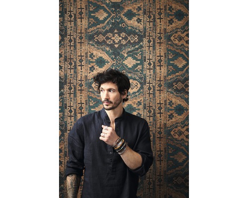 Mann vor einer gemusterten Wandverkleidung