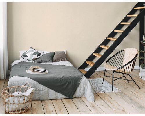 Schlafzimmer mit Bett, Leiter und Rattansessel auf Holzboden