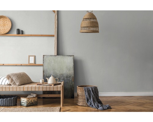 Wohnraum mit Holzregal, Korbmöbeln, Textilien und abstrakter Malerei