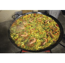 Paella mit Meeresfrüchten, Gemüse und Reis in einer grossen Pfanne.