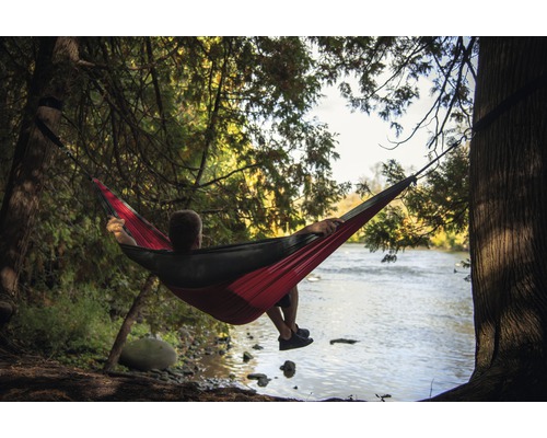 Mann entspannt in einer Hängematte am Flussufer.