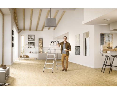 Homme avec lampe et échelle de sécurité en aluminium dans un salon lumineux