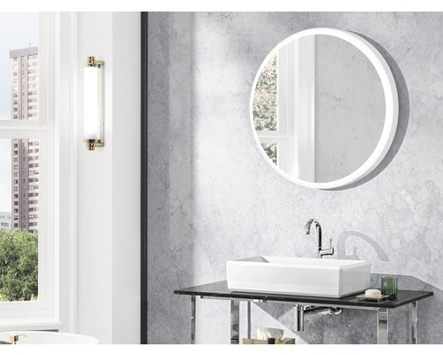 Salle de bain avec miroir rond, vasque à poser et applique murale.