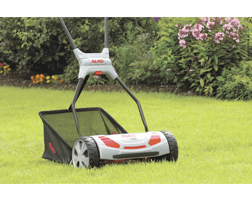 Scarificateur AL-KO sur pelouse avec des fleurs en arrière-plan