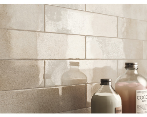 Wandfliesen in einer hellen Farbe und zwei Flaschen mit Pflegeprodukten im Badezimmer.