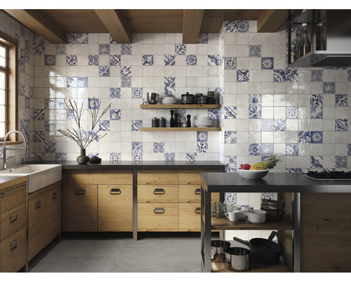 Helle Küche mit Fliesenwand in blau-weissem Muster, Holzschränken und Kochinsel.