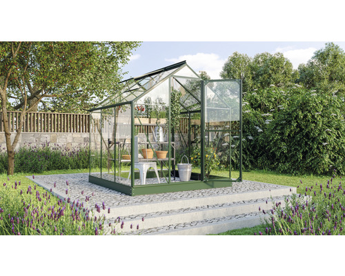 Gewächshaus im Garten mit Pflanzen und Gartenwerkzeugen