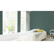 Schlafzimmer mit grüner Vliestapete, Bett, Fenster und Stuhl.