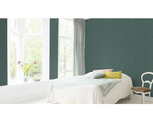 Chambre avec papier peint intissé vert, lit, fenêtre et chaise.