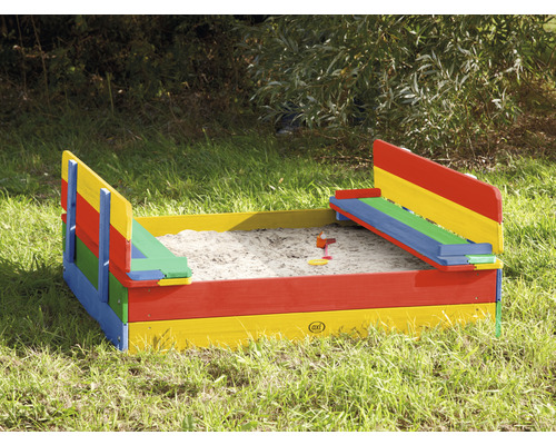 Bac à sable rempli avec cadre en bois multicolore dans le jardin