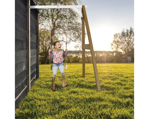 Fille se balançant sur une balançoire en bois dans le jardin.