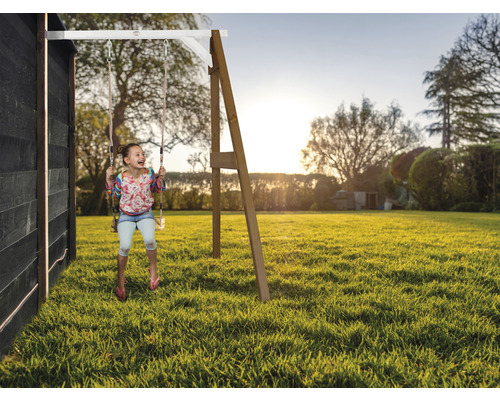 Fille se balançant sur une balançoire de jardin dans le jardin