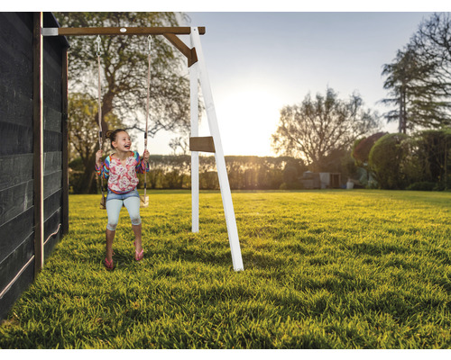 Fille se balançant sur une balançoire en bois dans le jardin.