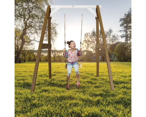 Fille se balançant sur une balançoire en bois dans le jardin.