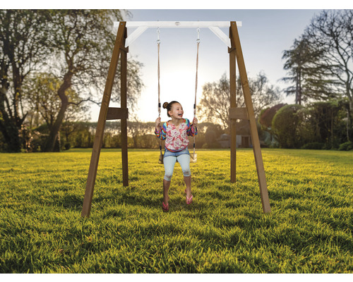 Fille se balançant sur une balançoire en bois dans le jardin.