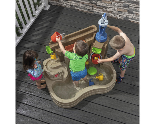 Des enfants jouent avec une table d''eau Step2 à l''extérieur avec pompe à eau et toboggan aquatique.