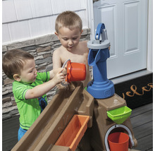Deux enfants jouent avec une table de jeu d''eau avec pompe et seau à l''extérieur.