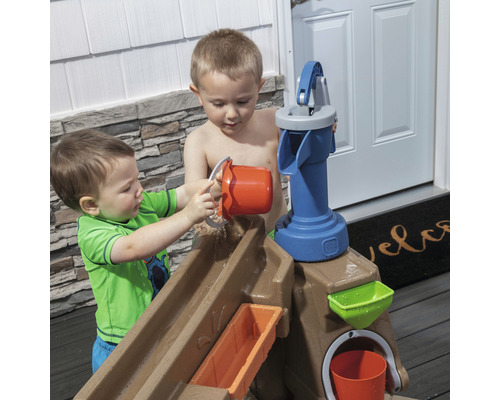 Deux enfants jouent avec une table de jeu d''eau avec pompe et seau à l''extérieur.