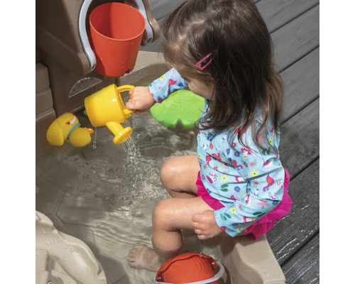 Fille jouant avec une table de jeu d''eau et un arrosoir jaune