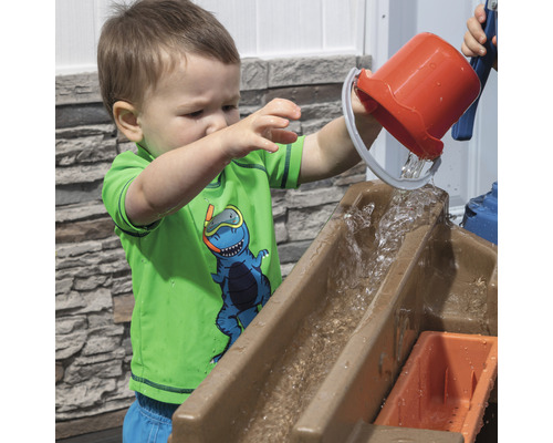 Bambin versant de l''eau d''un seau dans une table de jeu