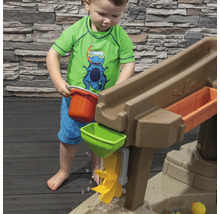 Un jeune enfant joue avec une table de jeu d''eau avec toboggan, entonnoir et seau dans le jardin