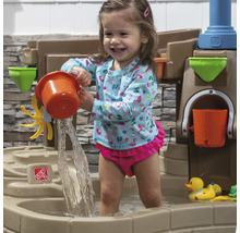 Fille jouant avec une table de jeu d''eau Step2 dans le jardin