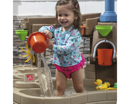 Fille jouant avec une table de jeu d''eau Step2 dans le jardin