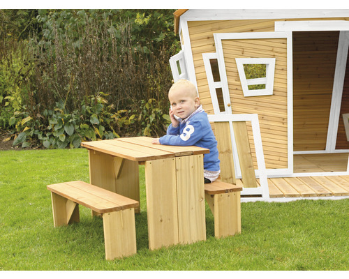 Ensemble de sièges pour enfants en bois avec table et bancs devant une cabane de jeu