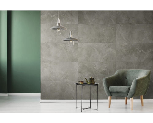 Wohnzimmer mit grauen Wandfliesen in Marmoroptik, Sessel und Pendelleuchten